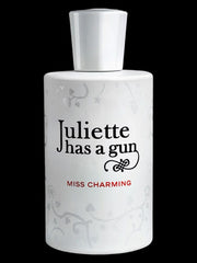 A white Juliette Has a Gun Miss Charming 100ml EDP bottle, featuring red text and subtle floral patterns, is inspired by Romano Ricci and stands out against a black background.