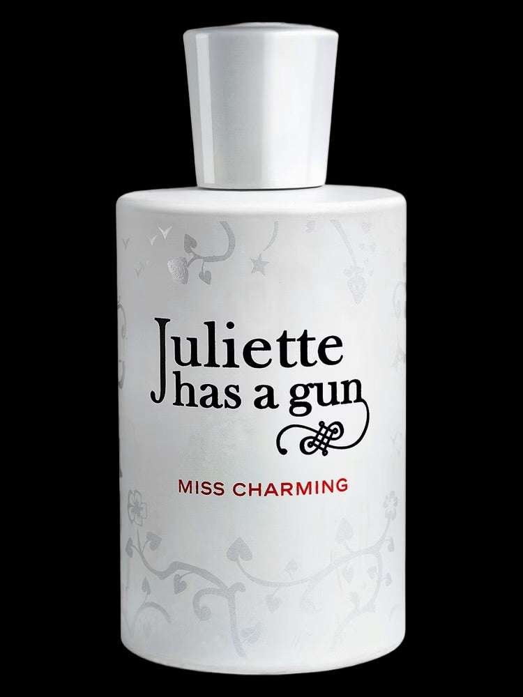 A white Juliette Has a Gun Miss Charming 100ml EDP bottle, featuring red text and subtle floral patterns, is inspired by Romano Ricci and stands out against a black background.