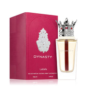 A bottle of Lattafa Dynasty 100ml EDP, with a crown-shaped cap, stands next to its pink textured box with silver details, showcasing the elegance of this unisex fragrance by Lattafa.