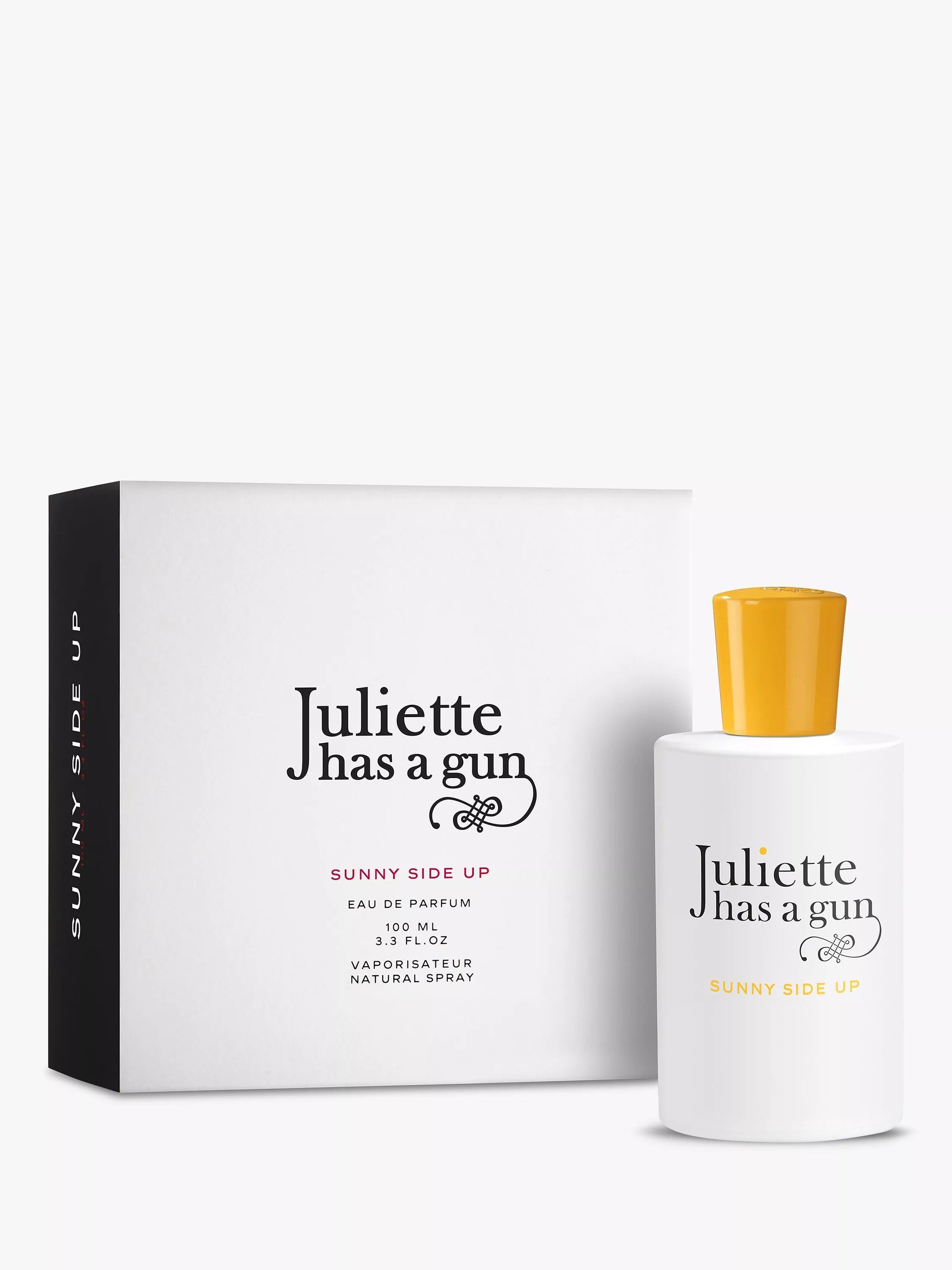A white bottle of Juliette Has a Gun Sunnyside Up 100ml EDP with a yellow cap is displayed beside its matching box, showcasing this musky women's fragrance from Juliette Has a Gun.