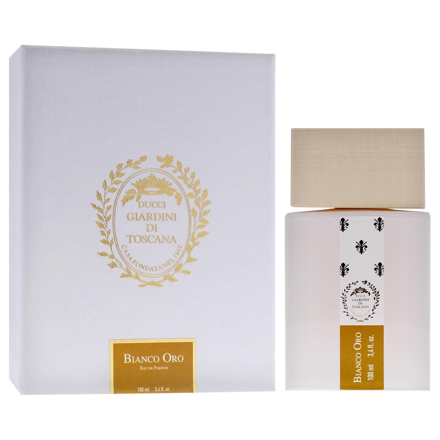 A white and gold box labeled "Giardini di Toscana Bianco Oro EDP" sits beside a matching bottle with a wooden cap and gold accents, reflecting the sophisticated unisex fragrance by Giardini di Toscana.