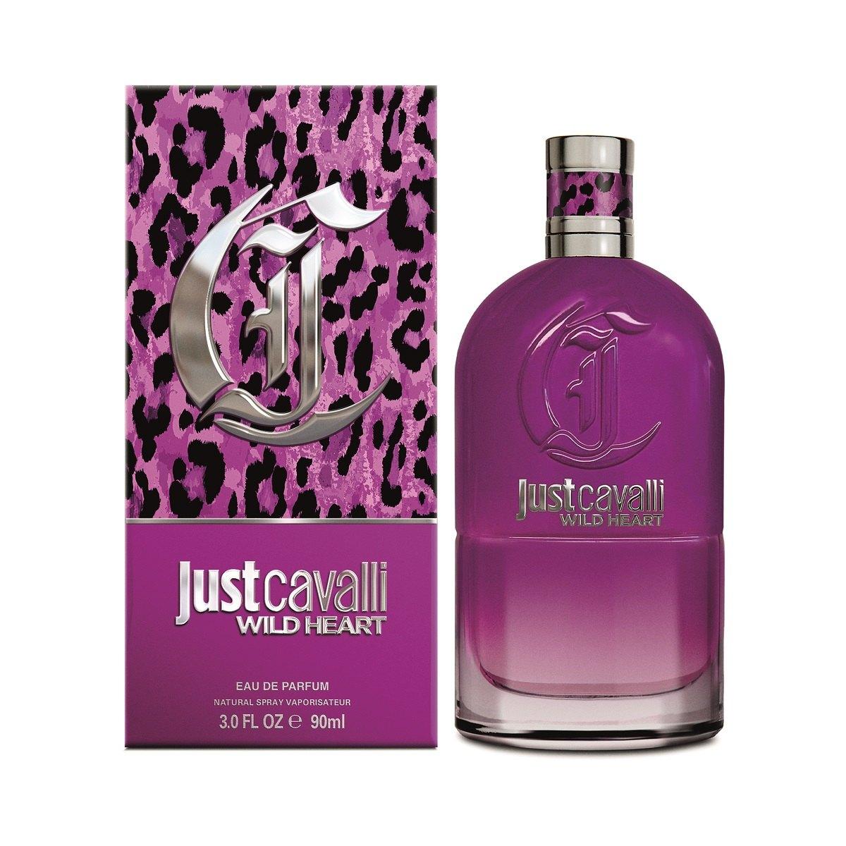 A bottle of Just Cavalli Wild Heart For Her 90ml EDP by Roberto Cavali is displayed beside its striking purple leopard-print box. The perfume features a matching metallic logo and cap, which perfectly complement its playful floral fruity scent.