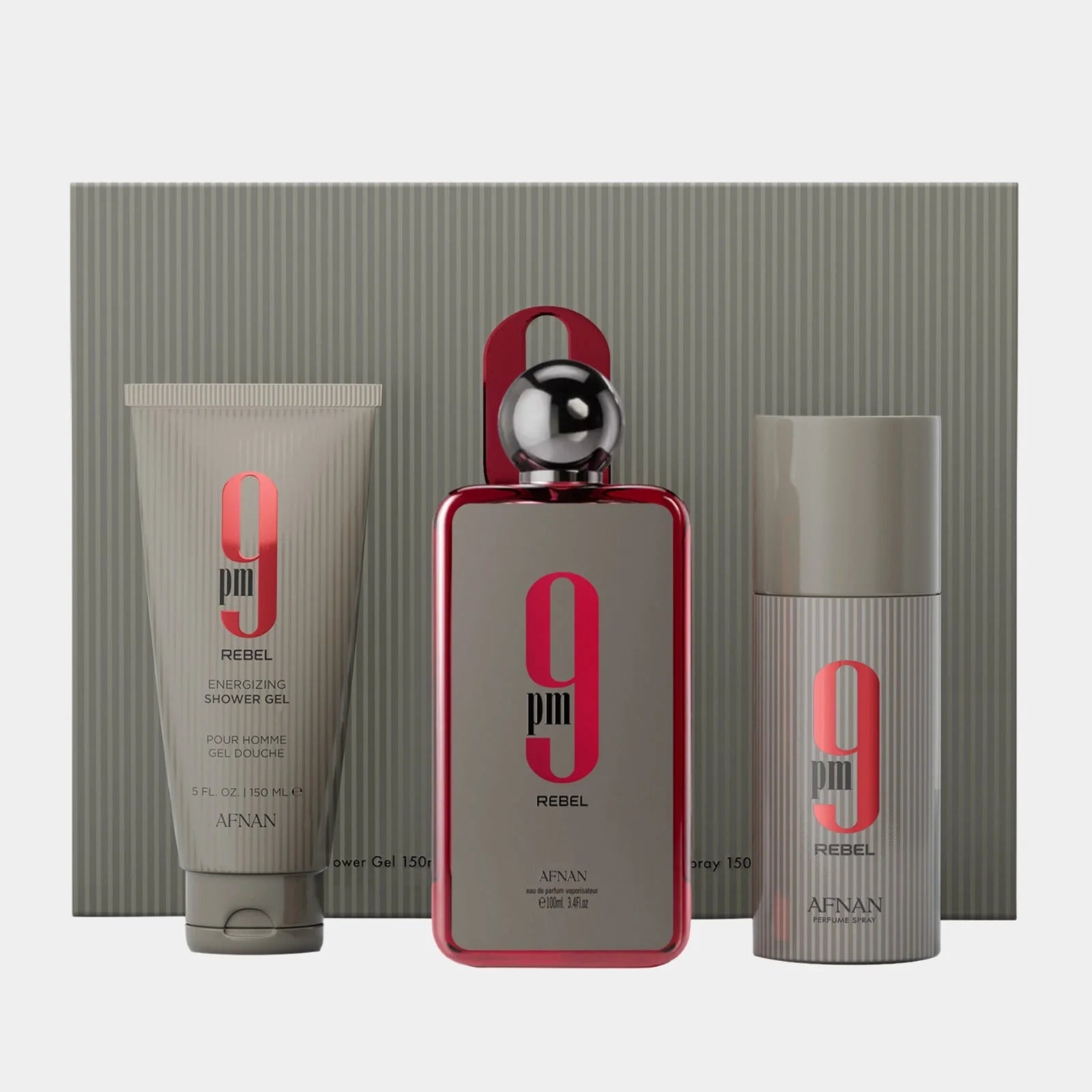 Afnan 9PM Rebel 100ml EDP Gift Set by Afnan, including shower gel, unisex Eau De Parfum spray, and deodorant—each in coordinated gray and red packaging—presented in front of a chic striped box.