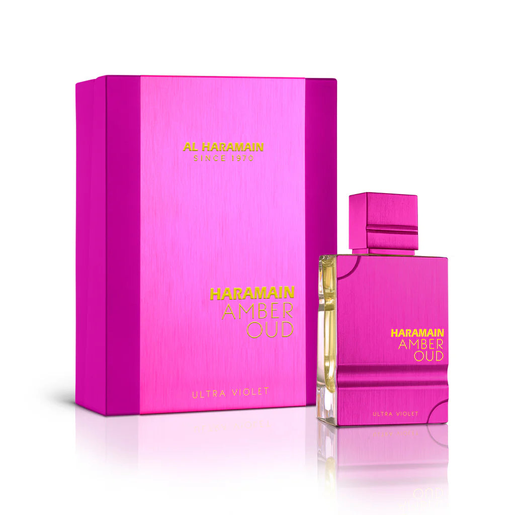 A pink, rectangular AL Haramain Amber Oud Ultra Violet 120ml EDP perfume bottle stands beside its matching pink and gold box, showcasing the luxury scent from AL Haramain.