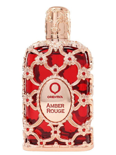 Decorative Orientica Amber Rouge Eau De Parfum bottle of "Amber Rouge," featuring red and clear glass patterns with a gold cap by Dubai Perfumes.