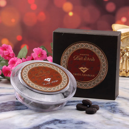 A box of chocolates and flowers, along with a ScentStory Swiss Arabian Bakhoor Bait Al Arab Incense, on a marble table.
