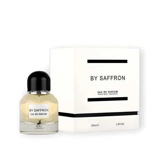 A 100ml bottle of Maison Alhambra By Saffron Eau de Parfum by Rio Perfumes is placed beside its white box with black labels. The bottle, adorned with a black cap and transparent body, beautifully showcases the golden liquid inside.