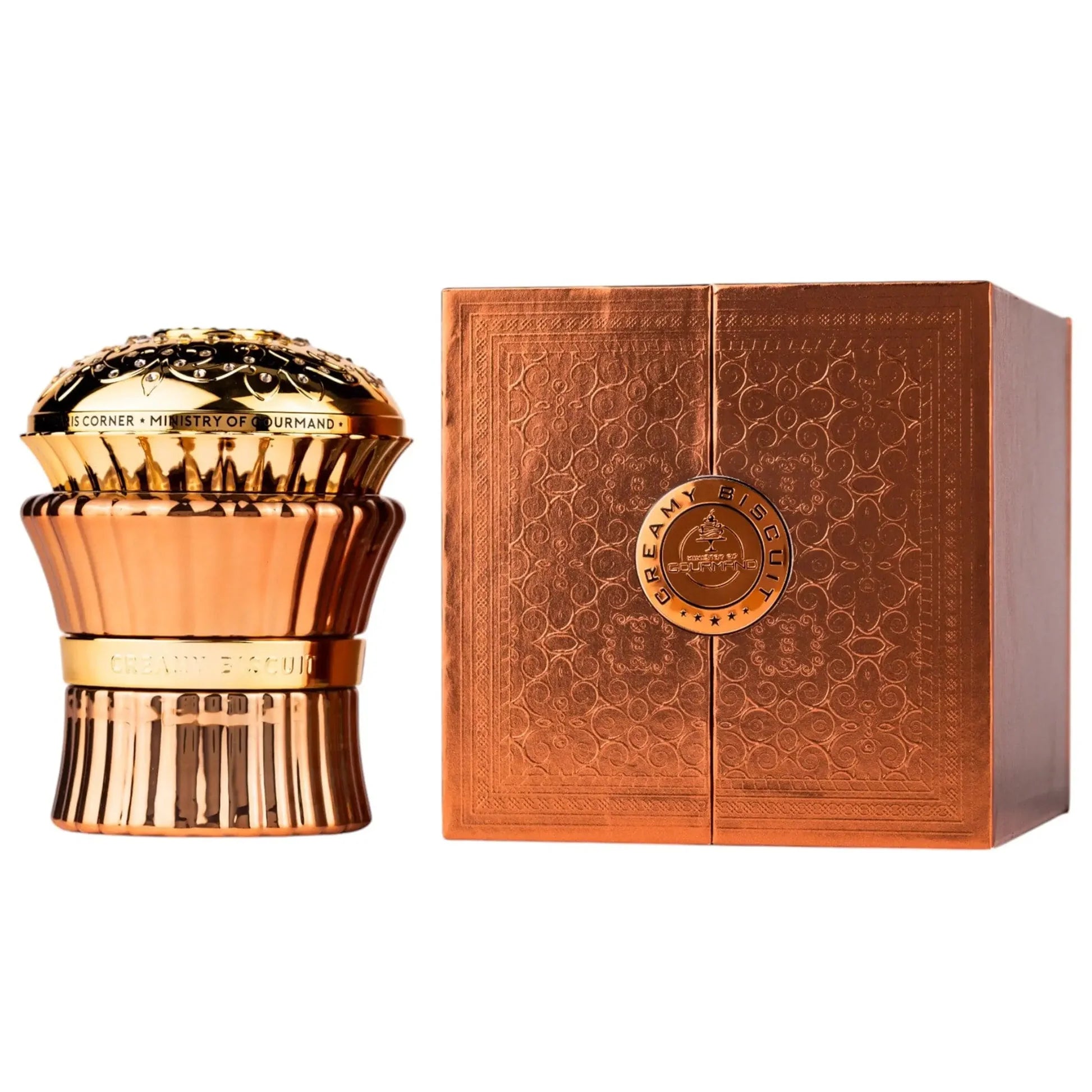 The Paris Corner Ministry of Gourmand Creamy Biscuit 100ml EDP sits in a gold and copper bottle with an ornate lid, accompanied by a matching box with geometric patterns, embodying this deliciously gourmand fragrance.
