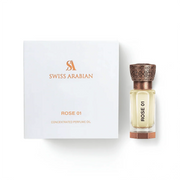 A square box labeled “Swiss Arabian Rose 01 Concentrated Oil” stands beside a clear glass bottle with an ornate cap, both carrying the “Rose 01” name. Created by Swiss Arabian, this concentrated oil surrounds you in a rich, elegant rose perfume for a truly luxurious floral experience.