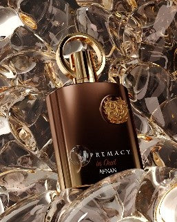 Afnan Supremacy in Oud 100ml Extrait de Parfum by Afnan, in a metallic brown bottle, rests on clear decorative glass pieces.