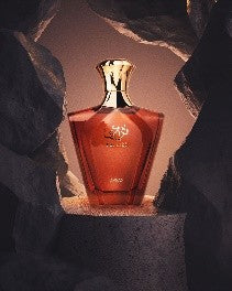 A 90ml Afnan Turathi Homme Brown Eau De Parfum bottle by Afnan stands on a stone pedestal, surrounded by dark rocks and warm lighting—a bold men's fragrance.