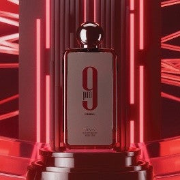 Afnan 9 AM Rebel Eau De Parfum stands boldly on a pedestal, framed by vertical and diagonal red neon lights, perfectly capturing the vibrant spirit of this dynamic men’s fragrance from Afnan.