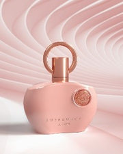 Afnan Supremacy Pink 100ml Eau De Parfum for women features a pink bottle with a gold circular cap and embossed text, set against a wavy light pink background—an elegant fragrance from Afnan.