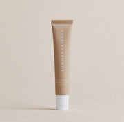 A tube of Summer Fridays Lip Butter Balm Vanilla by Summer Friday stands upright on a light beige background.