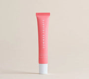 A tube of Summer Fridays Lip Butter Balm Pink Sugar by Summer Friday, in a pink shade with a white cap, stands upright against a beige background.