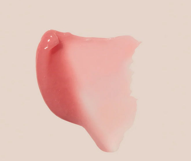 A swipe of Summer Fridays Lip Butter Balm Pink Sugar by Summer Friday, a glossy pink balm with a scent reminiscent of pink sugar, on a light beige background.