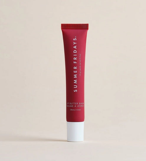 The Summer Friday Lip Butter Balm Cherry stands upright against a beige background, highlighting this nourishing lip mask for soft, hydrated lips.