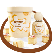 A bottle and tub of Tubbees Tres Leches EDP by Tubbees are displayed amidst squares of tres leches cake on a white surface with a brown circular border, perfectly capturing the delectable essence of this gourmand fragrance. This vanilla-rich perfume evokes the creamy sweetness of your favorite dessert with every spritz.