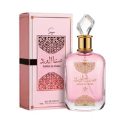 A pink perfume bottle adorned with gold accents and Arabic script stands beside a matching pink and gold box labeled "Sabah Al Ward Sugar." This Eau De Parfum, Al Wataniah Sabah Al Ward Sugar 100ml EDP by Al Wataniah, radiates Oriental Floral elegance—ideal for those who value luxurious scents and sophisticated design.
