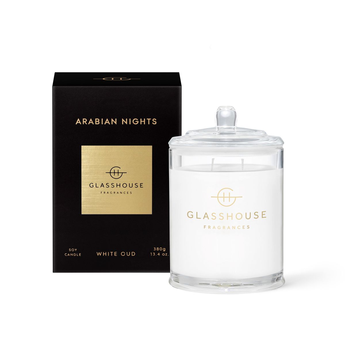 The Glasshouse Arabian Nights 380g Soy Candle comes in a clear glass jar with lid, displayed beside its black and gold box—featuring vibrant notes inspired by a carnival with hints of lime and passionfruit.