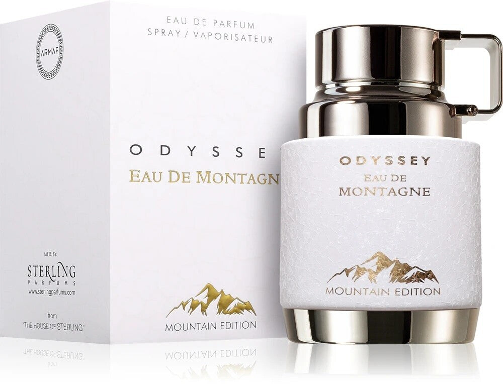 A white and silver bottle of Armaf Odyssey Eau De Montagne 100ml EDP for men stands beside its matching box, both showcasing gold mountain graphics and labeled “Mountain Edition.”.