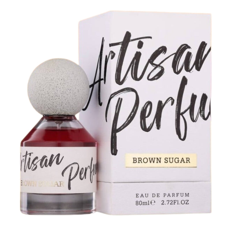 A bottle of Fragrance World Brown Sugar Artisan Perfumery 80ml Eau De Parfum stands next to its box, both featuring bold black lettering and gold accents that highlight the refined style of the Fragrance World brand.