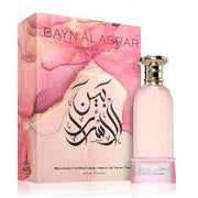 A pink bottle of Paris Corner Bayn Al Asrar 80ml Eau De Parfum, a fruity floral unisex scent, sits in front of its matching pink and gold packaging decorated with Arabic script.