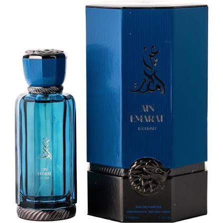 A striking blue perfume bottle labeled “Ain Emarat” sits beside its coordinating blue and black box, both adorned with Arabic script and intricate decorative accents. This sophisticated presentation embodies the rich essence of Al Wataniah Ain Emarat Extrait 100ml EDP—a concentrated sweet, spicy, lavender, vanilla, and woody fragrance from Al Wataniah—making it an alluring choice for those drawn to refined Middle Eastern scents.