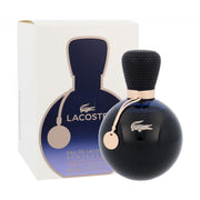 A round, dark Lacoste Eau De Lacoste Sensuelle 50ml Eau De Parfum bottle with a textured cap and tag sits in front of its matching box—a sophisticated women’s fragrance.