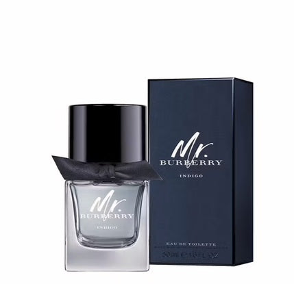 A 50ml bottle of Burberry’s Mr Burberry Indigo Eau De Toilette, featuring a black cap and ribbon, is showcased beside its dark blue packaging box.