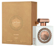 A white Lattafa Nebras Elixir 100ml EDP bottle with a copper cap and emblem is displayed beside a copper-toned box, featuring a solar gourmand scent with warm vanilla and musk notes.