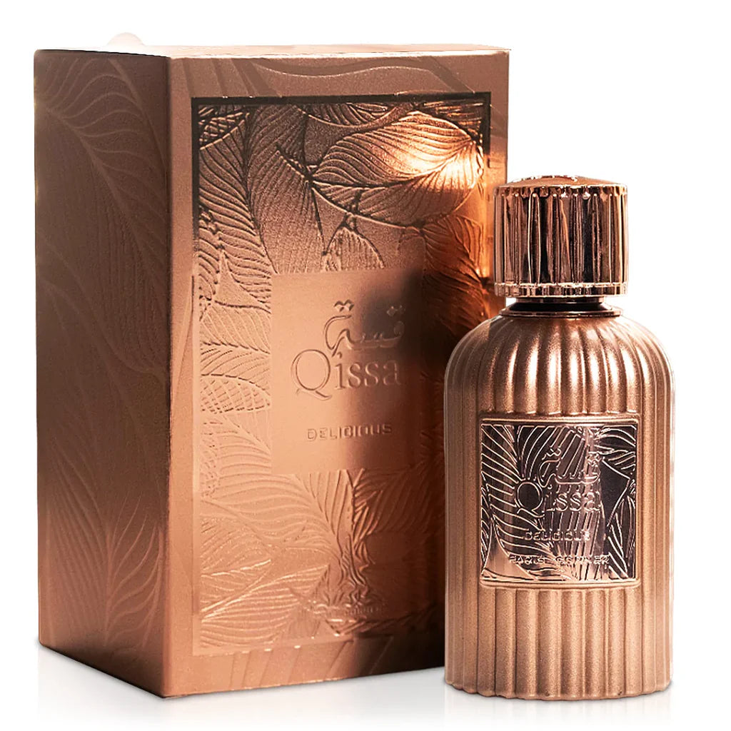 A metallic rose gold Paris Corner Qissa Delicious 100ml Eau De Parfum bottle with vertical ridges and an embossed label stands next to a matching box with leaf patterns, presenting a sophisticated unisex fragrance.