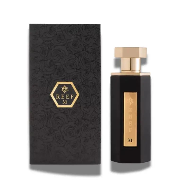 A rectangular black and gold bottle of Reef 31 100ml EDP by Reef is displayed beside its matching floral-patterned box, highlighting the sophistication of this unisex Eau De Parfum.