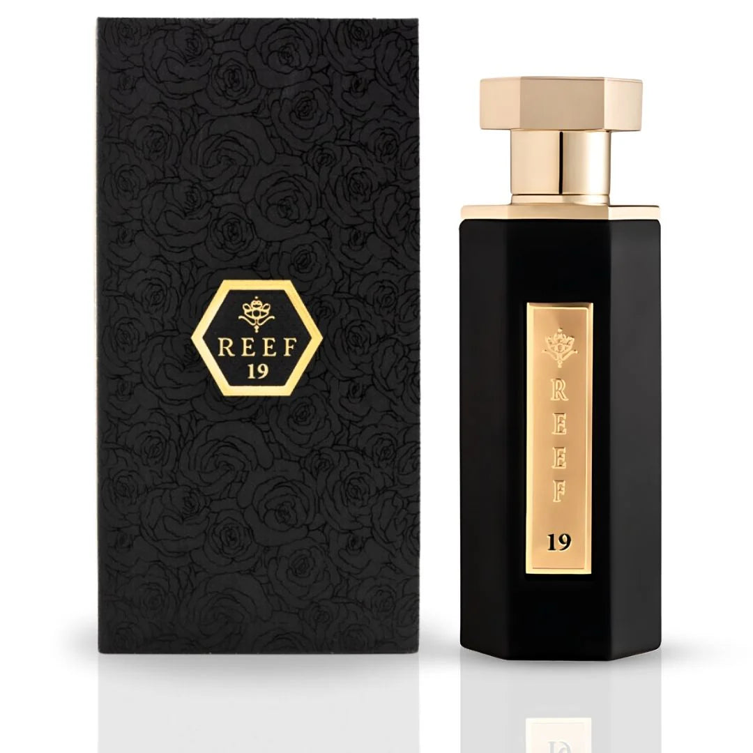 A black and gold Reef 19 100ml EDP bottle stands beside its matching textured box with a gold hexagonal label and rose pattern, showcasing this distinctive unisex fragrance from Reef.