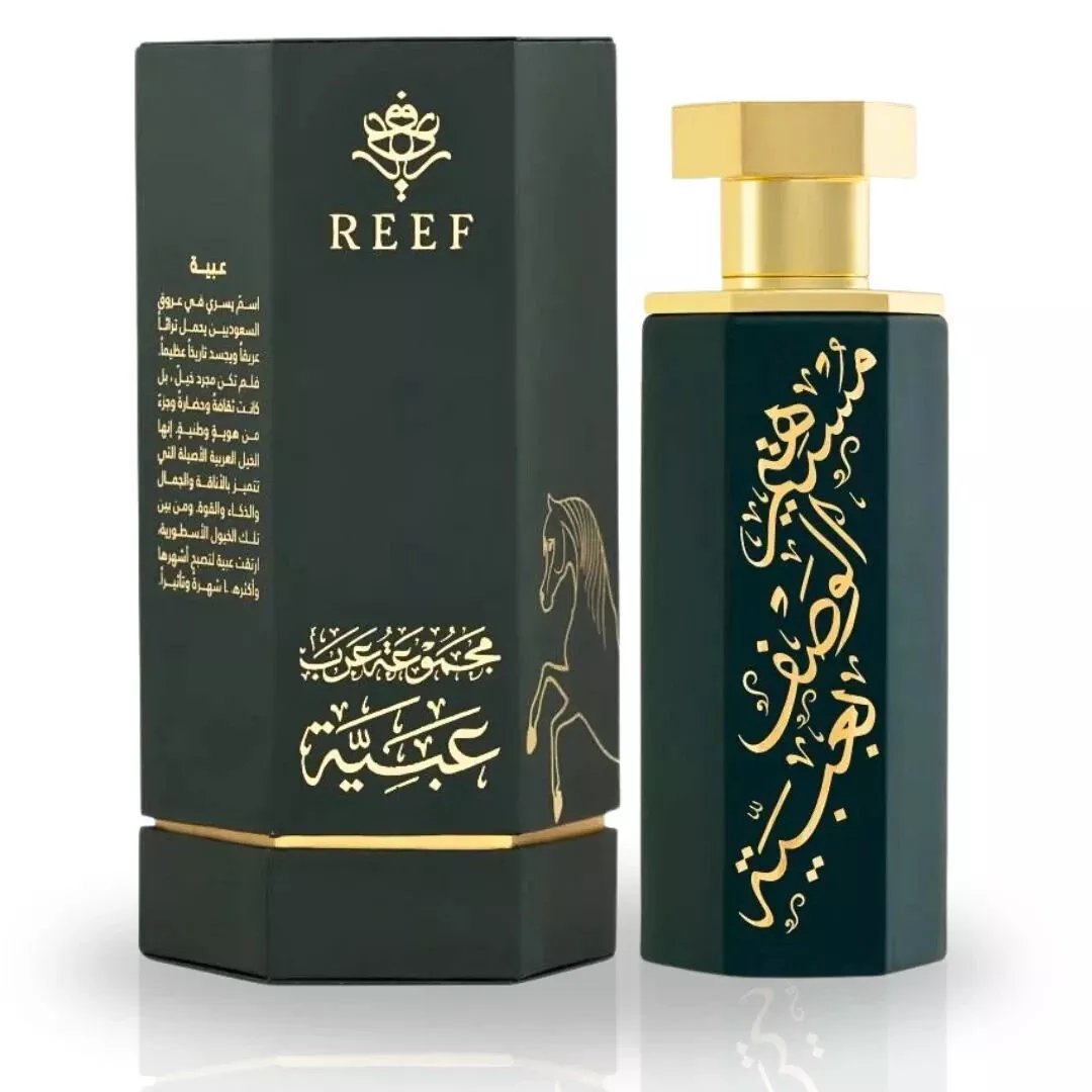 The Reef Arab Collection Obaiah 100ml EDP by Reef features a dark green hexagonal bottle with gold Arabic calligraphy and cap, next to a matching box with gold designs and a horse illustration. A captivating unisex fragrance.
