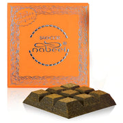 A bright orange box labeled "Bakhoor Nabeel Touch Me" by Rio Perfumes sits behind a segmented block of brown incense bukhoor, made from fragrant woods, 40GM.