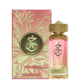 A gold-capped bottle of Paris Corner Khair Peach Delulu 100ml EDP with pink liquid stands before its matching pink and gold floral box, featuring Arabic script. This unisex fragrance by Paris Corner offers a fruity gourmand scent.