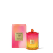 The Glasshouse Neon Rays Soy Candle 380g comes in a pink and orange gradient jar with a matching box. It's a Mango Bellini scent, capturing the tropical fruit allure.