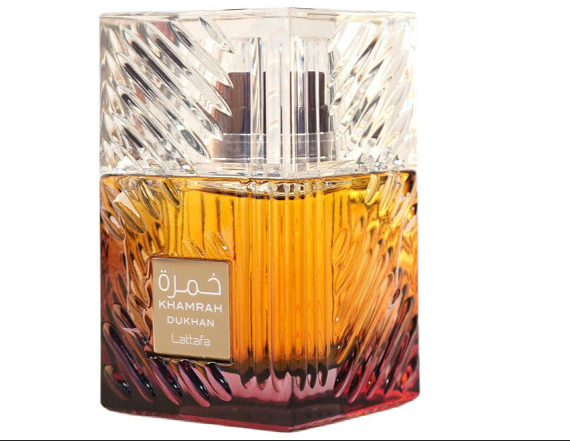 A square glass bottle labeled "Lattafa Khamrah Dukhan 100ml Eau De Parfum" features a yellow to red gradient, reflecting this unisex fragrance by Lattafa.