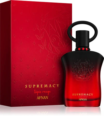 The Afnan Supremacy Tapis Rouge 90ml EDP by Afnan is shown in a red and black bottle beside its matching red box with gold text, highlighting this floral fruity fragrance for women.