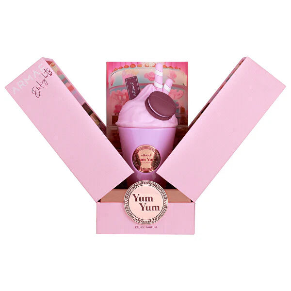 A pink milkshake-shaped bottle labeled "Yum Yum Eau De Parfum" sits in an open pink box with straws and macaron designs. This playful women's fragrance is Armaf Delights Yum Yum 100ml EDP by Armaf.