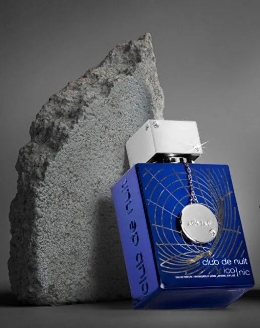 An Armaf Club De Nuit Blue Iconic 105ml Eau De Perfum bottle sitting next to a rock.