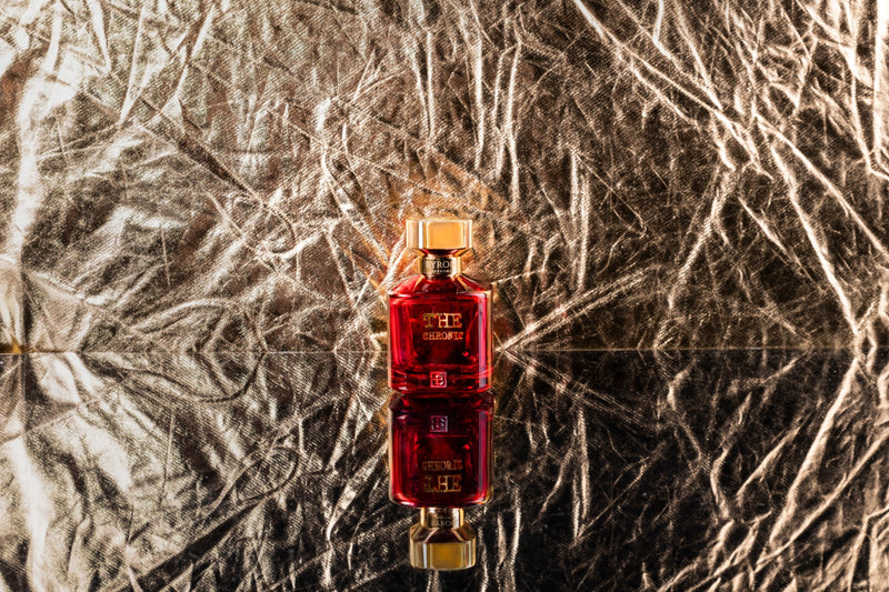 Load image into Gallery viewer, A bottle of Byron Parfums Parfums The Chronic 75ml Extrait De Parfum, a rich red liquid from Byron Parfums, elegantly displayed on a shiny surface.
