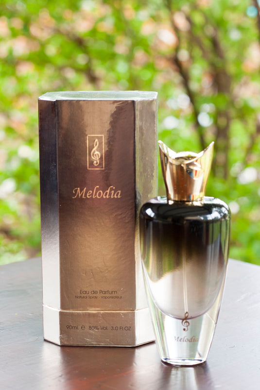 A bottle of Paris Corner Melodia 90ml Eau De Parfum by Dubai Perfumes sits on a table next to a box.