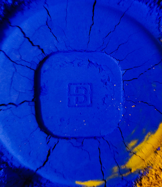 A blue plate with the letter b on it, featuring a Byron Parfums Mula Mula fragrance.