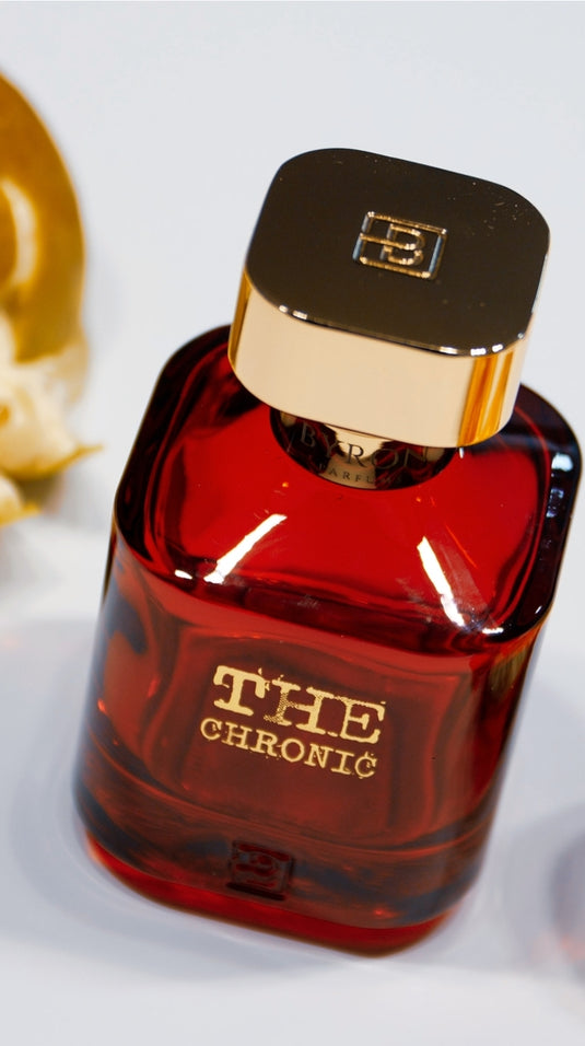 A bottle of Byron Parfums' The Chronic 75ml Extrait De Parfum sits next to a bottle of Mula Mula perfume on a table.