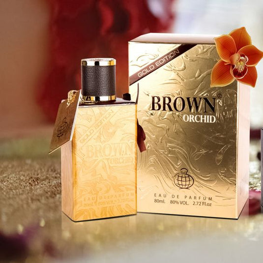 A Fragrance World Brown Orchid Gold Edition 80ml Eau de Parfum bottle sits on a table next to a box.