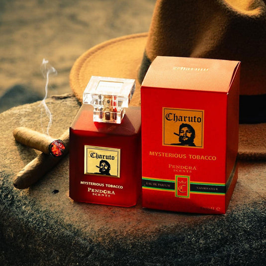 A box of Pendora cigars and a hat on a rock, emanating the fragrance of Pendora Charuto Mysterious Tobacco 100ml Eau de Parfum.