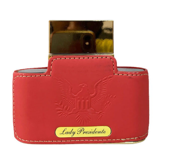 Load image into Gallery viewer, A red leather wallet adorned with an Emper Lady Presidente Pour Femme 80ml perfume from Rio Perfumes.
