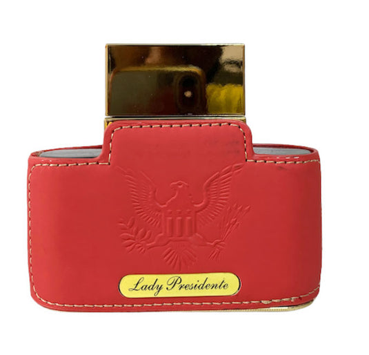 A red leather wallet adorned with an Emper Lady Presidente Pour Femme 80ml perfume from Rio Perfumes.